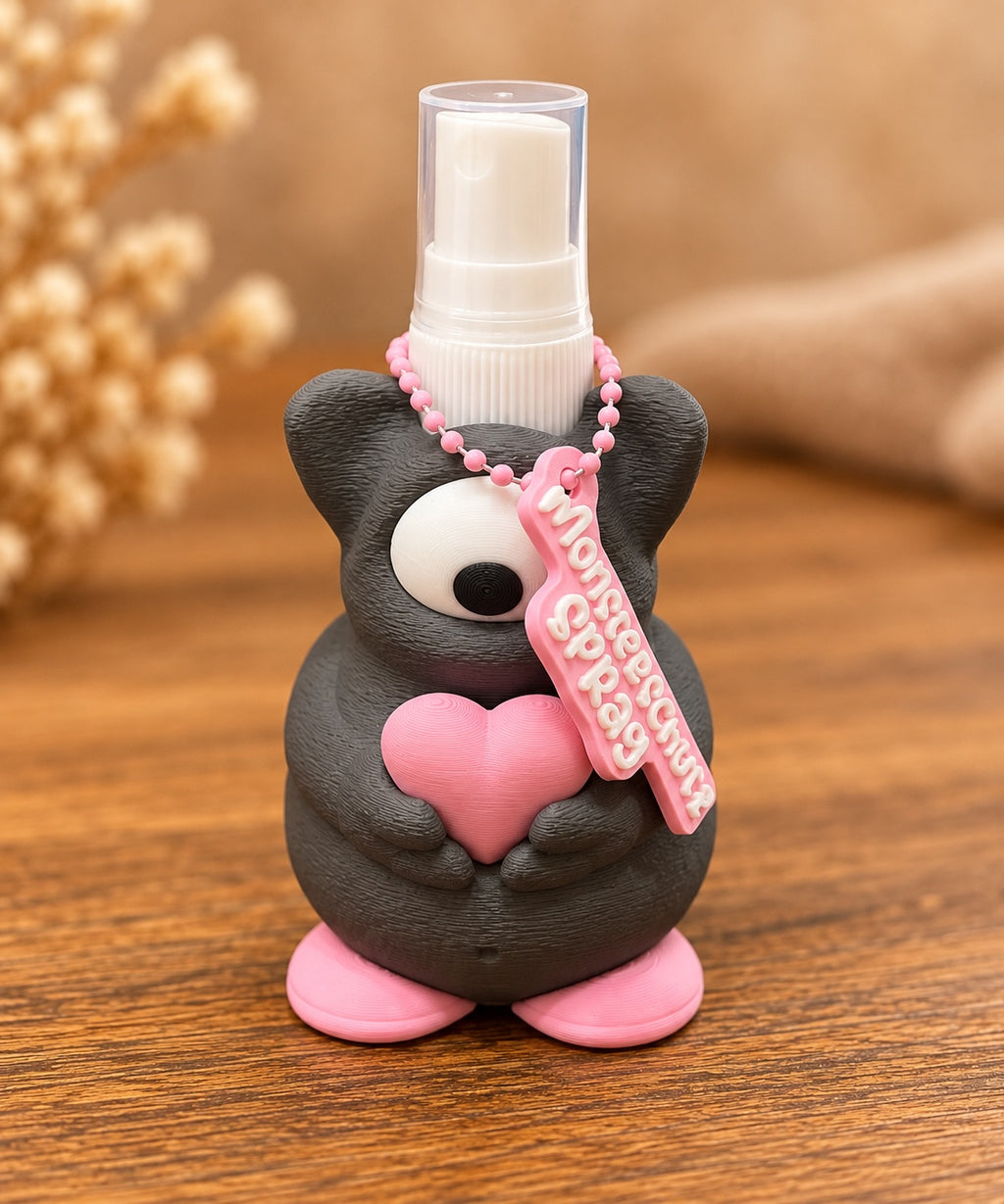 Dunkelgrauer Monster-Sprayhalter von vorne mit Sprühflasche und Anhänger