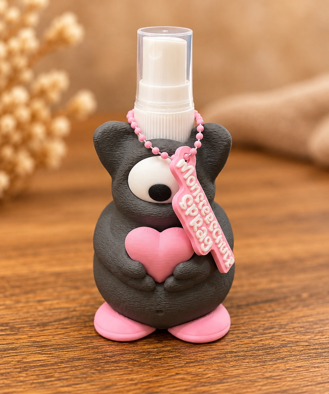 Dunkelgrauer Monster-Sprayhalter von vorne mit Sprühflasche und Anhänger